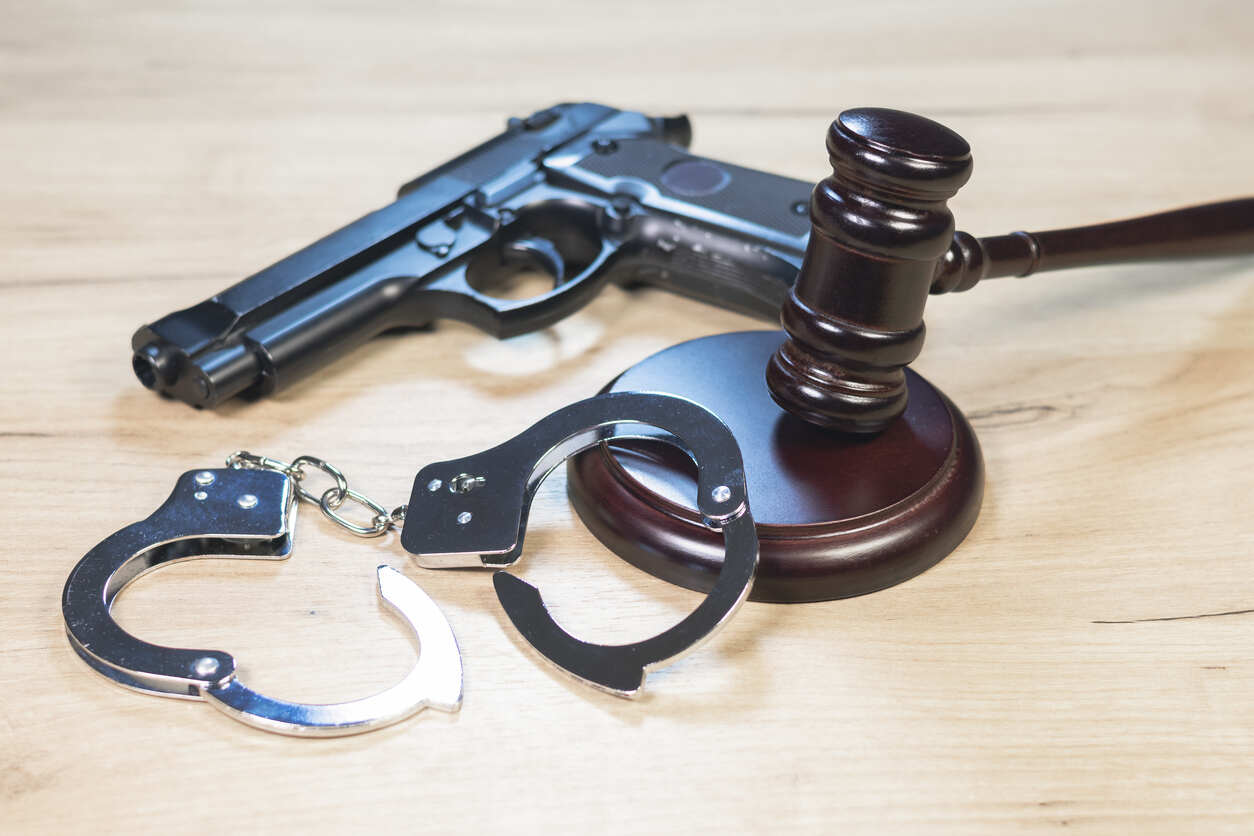 Kennesaw Criminal Defense Lawyer Objects representing the criminal justice system: a firearm, handcuffs, and a gavel, often associated with criminal defense lawyers.
