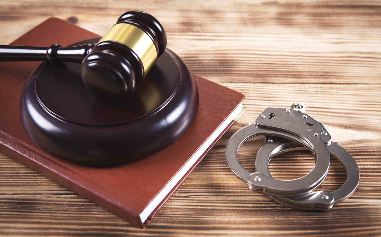 A judge's gavel on a law book next to handcuffs, symbolizing the legal services of a criminal defense lawyer in Sandy Springs.