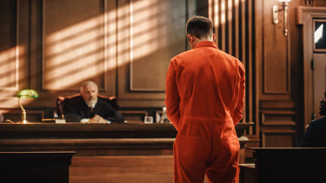 Defendant in orange jumpsuit standing before the judge in a courtroom, symbolizing criminal charges and accusations in Georgia legal proceedings.