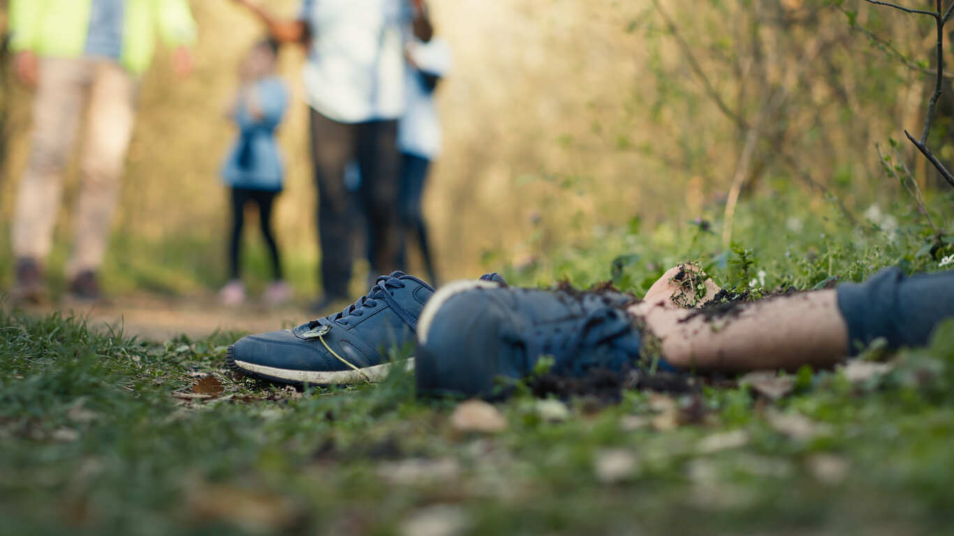 Murder & Manslaughter Scene showing shoes and a partially buried body in a forest, symbolizing the serious nature of murder and manslaughter cases.